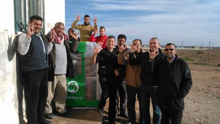 Happy people standing next to a Homebiogas system in Jordan