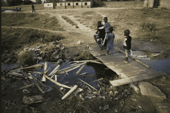 Children play over an open sewer in the slum