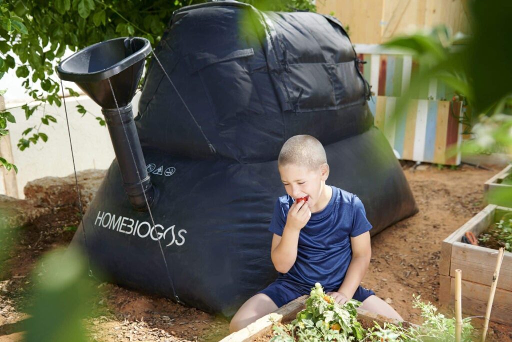 A child sits next to a Homebiogas system